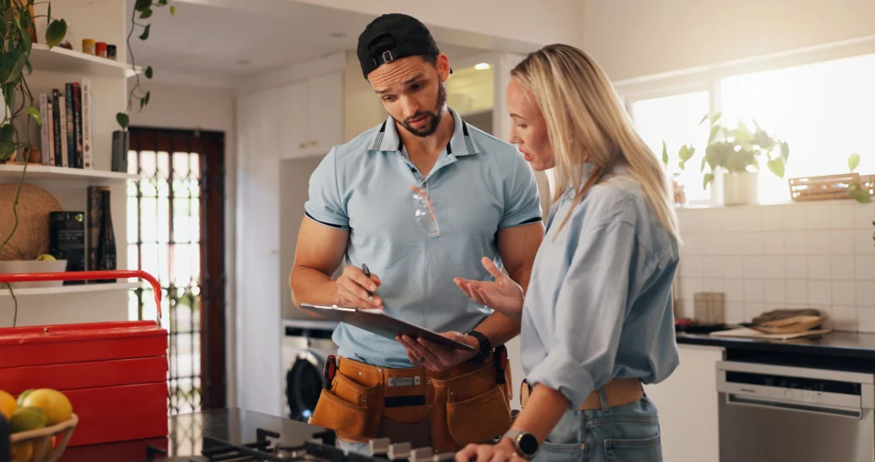 Man & woman in kitchen speaking looking at clipboard